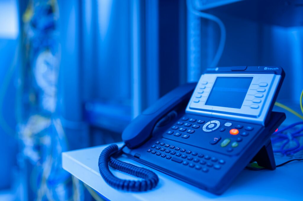 Close-up of a modern office phone in blue lighting. Ideal for tech and business themes.