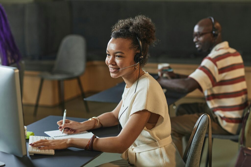 Cheerful woman in a call center using a headset and computer while working.