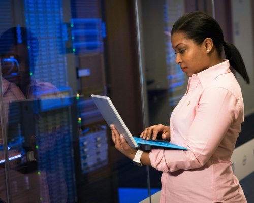 A focused software engineer working on a laptop in a server room, reflecting dedication in tech.