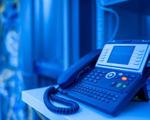 Close-up of a modern office phone in blue lighting. Ideal for tech and business themes.