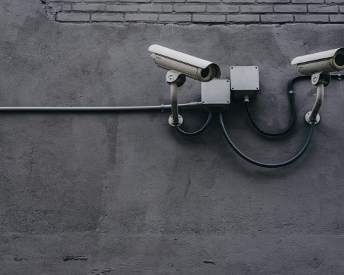 Two surveillance cameras mounted on a concrete wall, highlighting security technology.